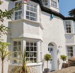 White exterior of a house with bay windows and potted plants at The Old Wash House in Dartmouth