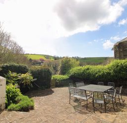 A garden with a table and chairs at Orchard Barn Salcombe