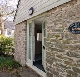 An entrance with a stone wall and sign at Orchard Barn in Salcombe