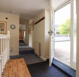 A hallway with a bench and door open at Orchard Barn Salcombe