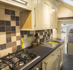 A kitchen with a gas stove sink and wall cabinets at Pixie Cottage in Dartmouth