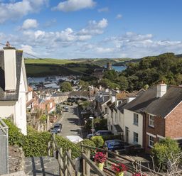 A street with houses and cars with a river and green hills in the background at Prospects in Salcombe