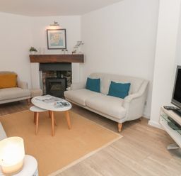 A living room with sofas a fireplace a television and a coffee table at Prospects in Salcombe