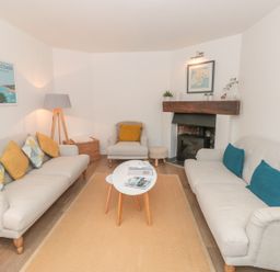 A living room with two sofas a chair a coffee table and a fireplace at Prospects in Salcombe