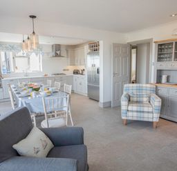 A kitchen and dining area with a table set for breakfast and armchairs at Raleigh House in Salcombe