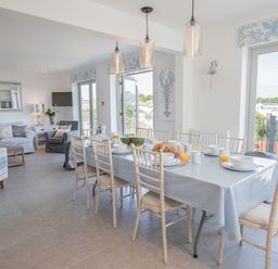 A dining room with a table set for breakfast and a living area with sofas at Raleigh House in Salcombe