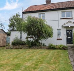 A front yard with a tree a lawn a pathway and a wooden shed in front of a white house at 7 Dale End Danby near Castleton