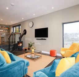 A living room with a sofa and fireplace at Postcard Lodge in Polruan