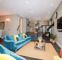 A living room with a sofa and dining area at Postcard Lodge Polruan