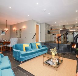A living room with a sofa, table, and dining area at Postcard Lodge Polruan