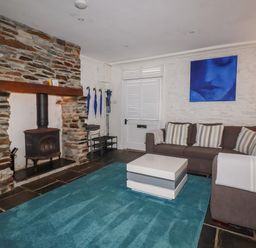 A living room with a fireplace and sofa at Rock House in Trebarwith Strand near Tintagel