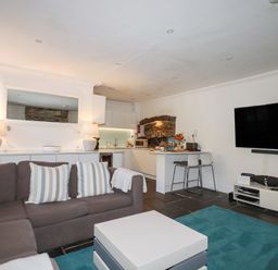 A living room with a sofa and kitchen area at Rock House in Trebarwith Strand near Tintagel