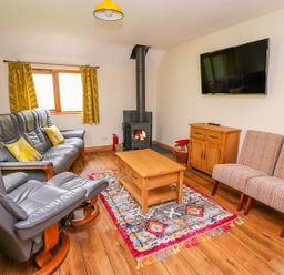 A living room with leather armchairs wooden coffee table and fireplace at Pines Pitch in Knighton