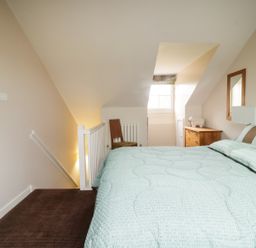 A bedroom with a bed a chair a dresser a window and a small wall mounted television at Ullswater 29 in Penrith