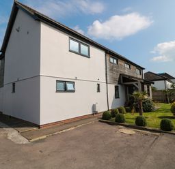 A modern two-story house with white and wooden exterior walls and a small garden with bushes at Longmynd in Gloucester