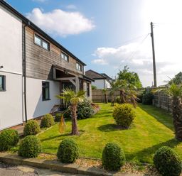 A garden with trimmed bushes and small palm trees next to a residential building at Longmynd in Gloucester