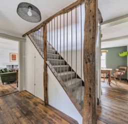 A living room featuring a staircase and green sofa at Spring Park Farmhouse in Launceston