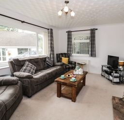 A living room with sofas a wooden coffee table a television and a fireplace at Ty Gilbert in Benllech