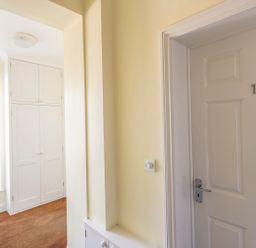 A hallway with a white door numbered 7 and built in white cupboards near a window at 1 Lyndhurst in Salcombe
