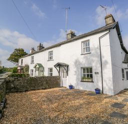 A white cottage with gravel driveway and stone wall at Rose Cottage Lowick Bridge
