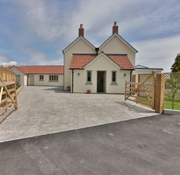 A house with red tiled roofs a paved driveway and wooden gates at the entrance at The Retreat in Lympsham