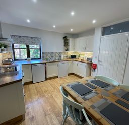 A kitchen with wooden floor cabinets countertop dining table and chairs at Stable Cottage in Shipham