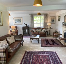 A living room with leather sofas and armchairs rugs a coffee table and a fireplace at Ribby Farmhouse in Lerryn