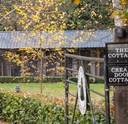A gated entrance with signs for The Cottage and Cream Door Cottage outside a building surrounded by trees and hedges at Cream Door Cottage Kidderminster