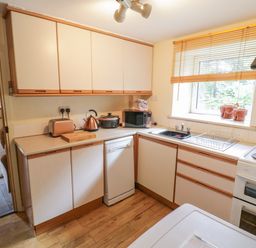 A kitchen with upper and lower cabinets toaster kettle microwave dishwasher sink and stove at Dyfi Cottage in Dolgellau