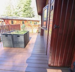An outdoor wooden deck with a rattan table and chairs near a wooden cabin at 40 Skiptory Howe in Troutbeck Bridge
