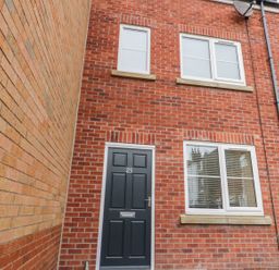 Front view of a brick house with a black door number 25 and three white framed windows at Valiant House in Scarborough