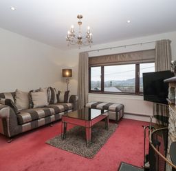 A living room with striped sofa and ottoman a glass coffee table a floor lamp and a stone fireplace at Tudor House in Symonds Yat