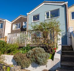 A row of houses with wooden siding and small front gardens with stairs and railings at 164 Cumber Close in Malborough
