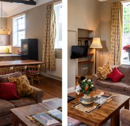 A living room with a brown sofa and wooden coffee table with flowers and books next to a kitchen area with a wooden dining table and chairs at The Old School in Gortin