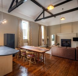 An open-plan living room with a kitchen island, dining table with chairs, sofa, and fireplace at The Old School in Gortin