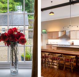 A vase with red flowers on a windowsill and a kitchen with wooden chairs and cabinets at The Old School in Gortin