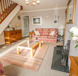 A living room with patterned sofas a coffee table a wooden sideboard and a fireplace at Kirkstone Cottage Outgate near Hawkshead
