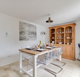 A dining area with a wooden table set with plates and glasses and transparent chairs at Fenders in Brewers Quay Harbour