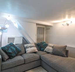 A living room with a gray sectional sofa and floor lamp at Fenders in Brewers Quay Harbour