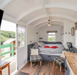 A small living space with a bed two chairs a kitchen countertop sink and door open to outside at Lady Bird Retreat in Skinningrove