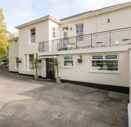 The exterior of a two-story building with a balcony and black door at Babbacombe Hall in Babbacombe