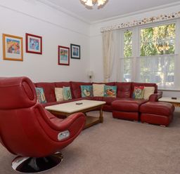 A living room with a red sofa and armchair at Babbacombe Hall in Babbacombe