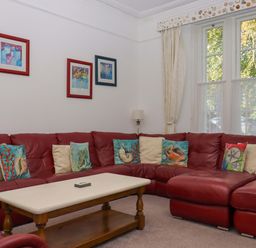 A living room with a red sofa and coffee table at Babbacombe Hall in Babbacombe