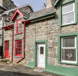 Stone cottages with red and green window frames and doors on a narrow street at Edrydd in Harlech