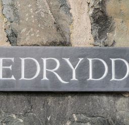A carved stone nameplate reading Edrydd mounted on a stone wall at Edrydd in Harlech