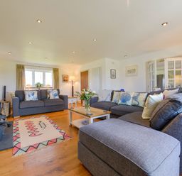 A living room with grey sofas a wooden coffee table and a window with curtains at Duffield in St Ann's Chapel