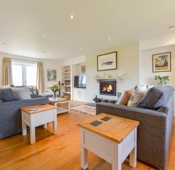 A living room with two gray sofas and wooden side tables near a fireplace and a television at Duffield in St Ann's Chapel