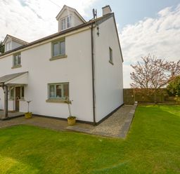 A white two-story house with green windows and a wooden porch surrounded by a lawn and small trees at Duffield in St Ann's Chapel