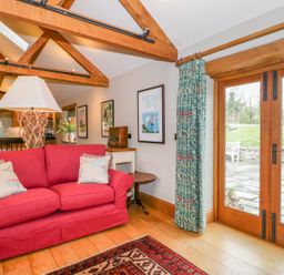 A living room with a red sofa and wooden beams at Middle Farm Annex in Long Bredy