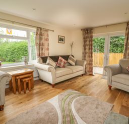 A living room with sofas and a rug near windows and glass doors at New Peny in Llandrindod Wells